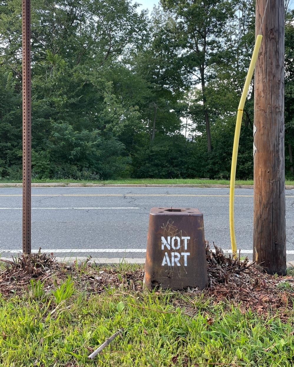 A streetlight base reading "NOT ART"