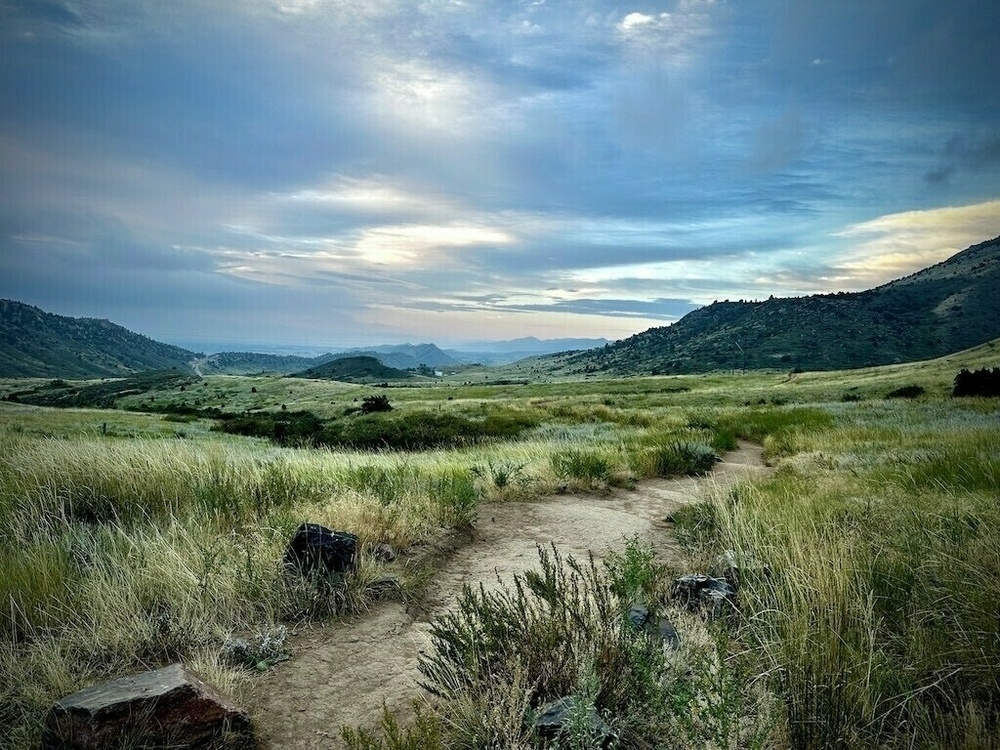 Landscape of clouded sky, mountains, and a grass prairie. 