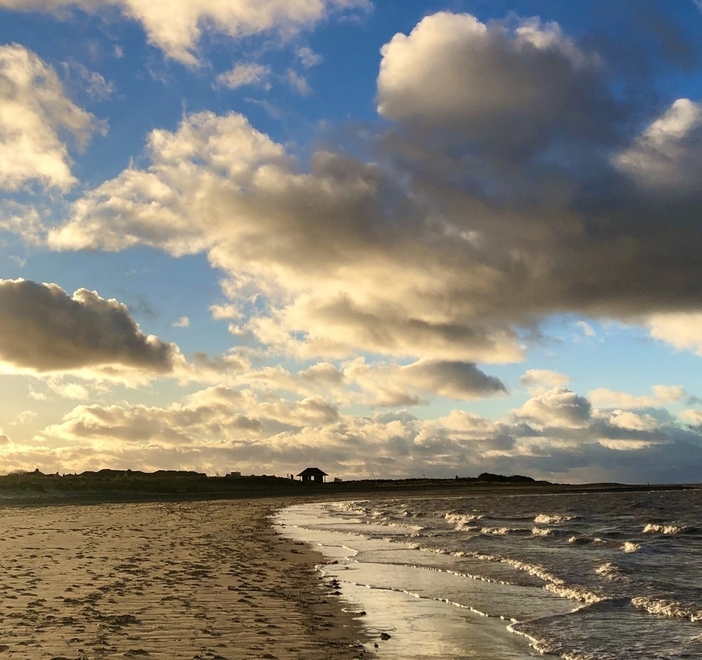 Seashore, clouds, sunshine and waves at golden hour 