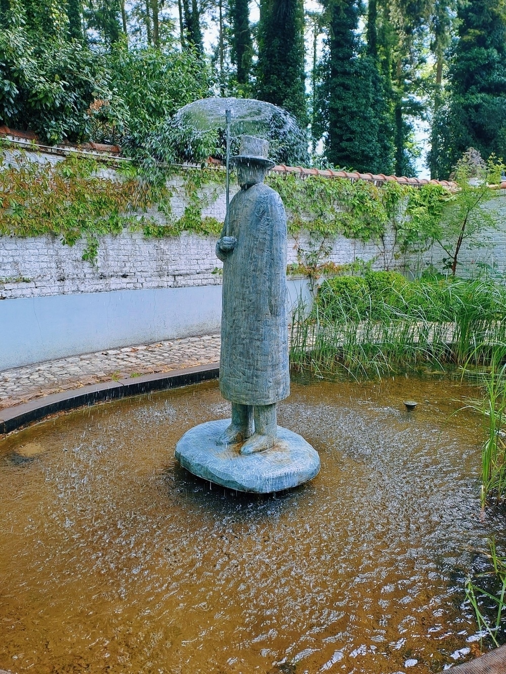 fontein,  een man die een paraplu gebruikt. het water komt uit de paraplu en vormt zo het scherm