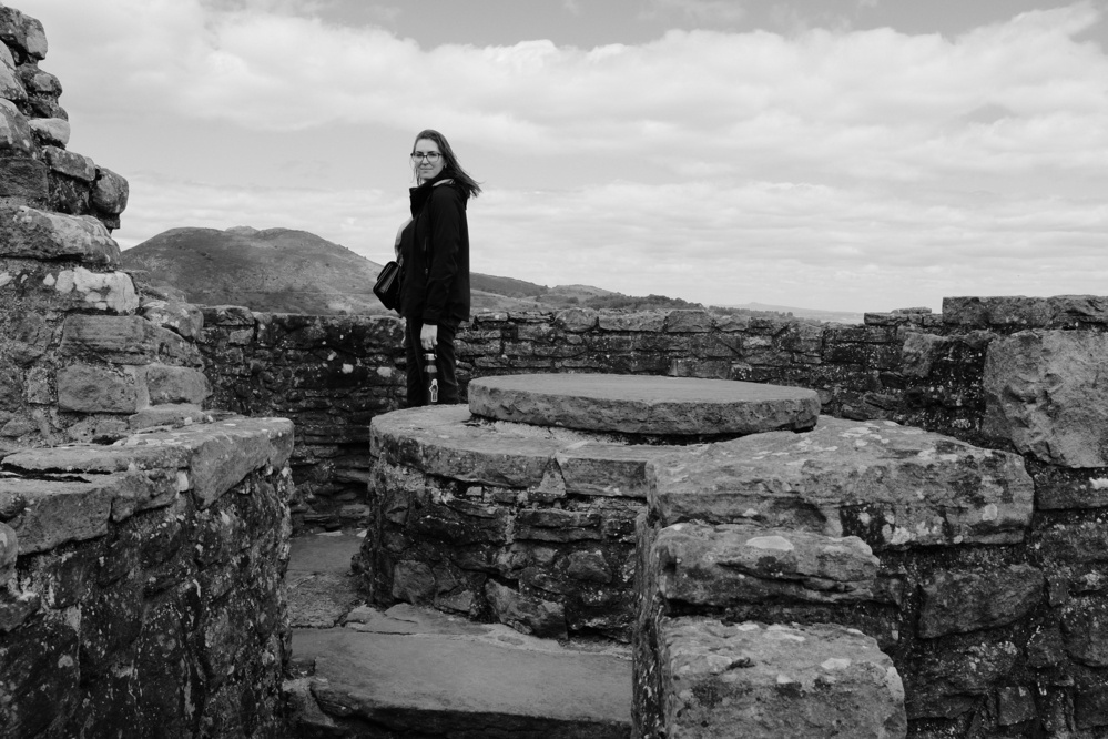 Jacqueline standing on a corner of the castle wall in black and white.