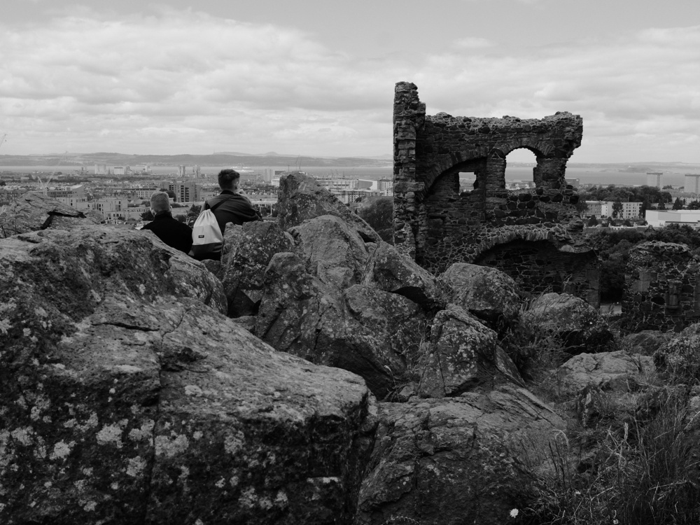 A couple of boys sit among the rocks in front of St. Anthony Chapel ruins.