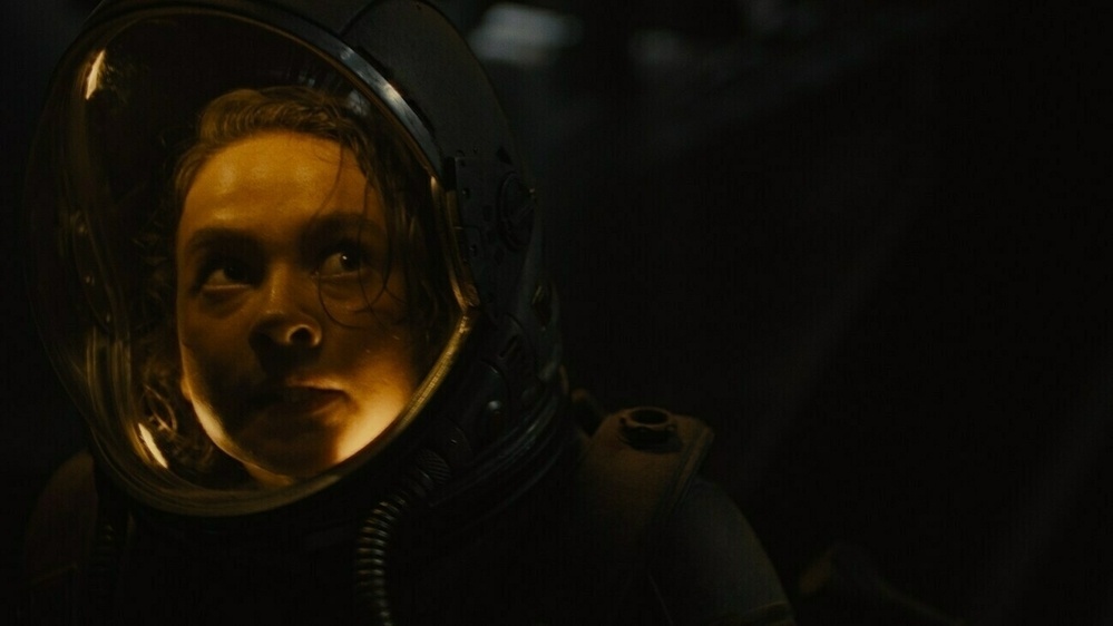 The protagonist, Rain, played by Cailee Spaeny, looks concerned in a space suit.