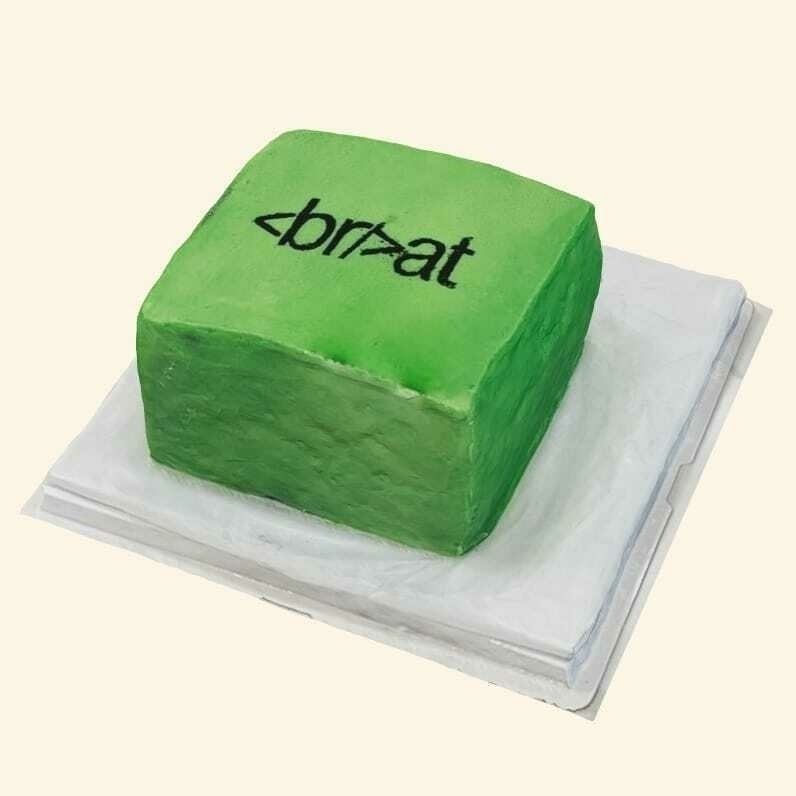 A green cake made to look like the cover of charli xcx's brat album but with an HTML element injected in the name so that it spells: opening angle bracket b r slash closing angle bracket a t.