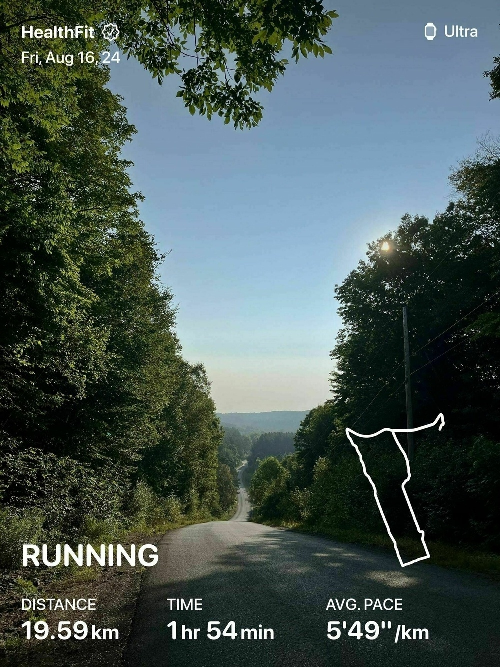 Auto-generated description: A peaceful, tree-lined road stretching into the distance under a clear sky, with overlay text displaying running metrics and a map route.