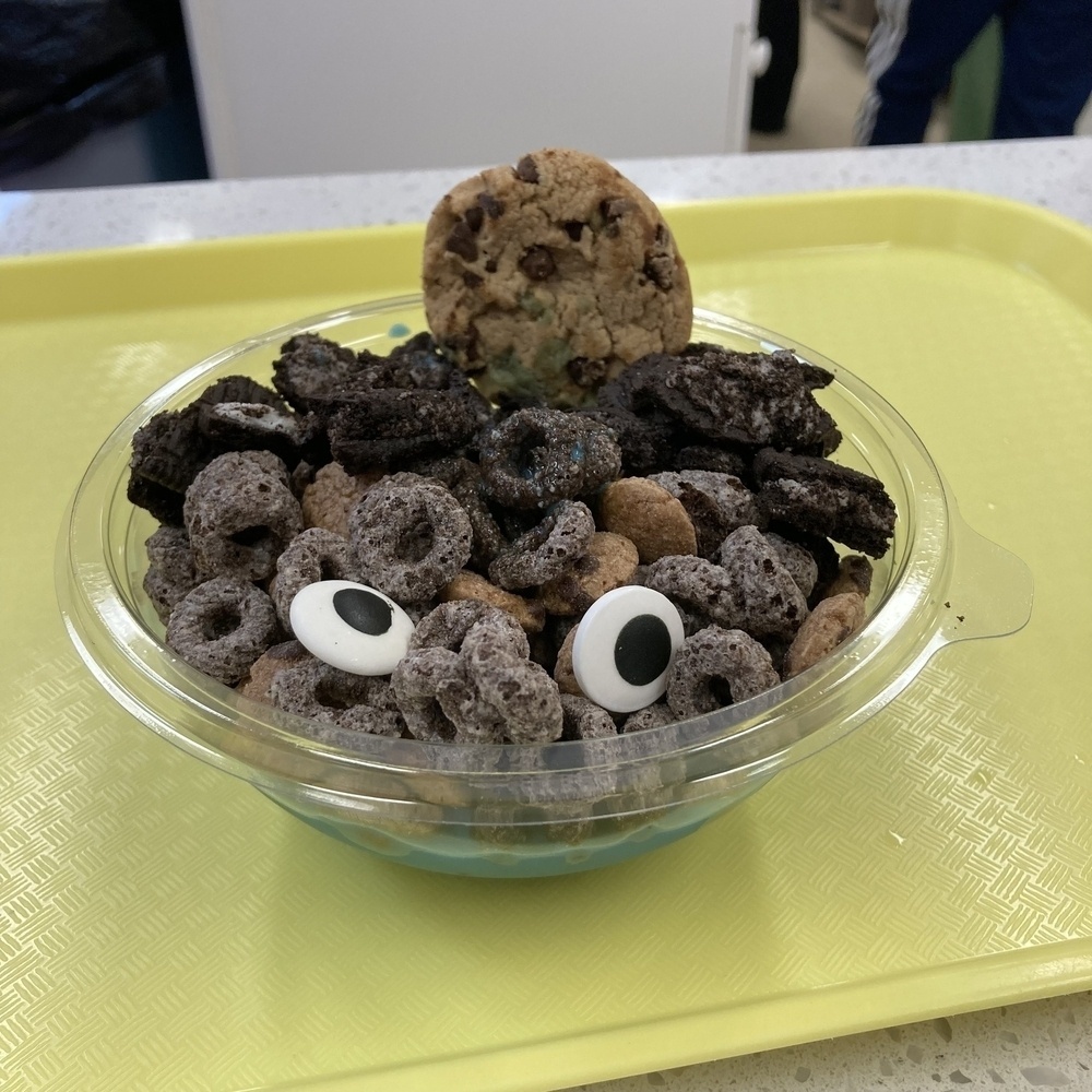 A bowl of chocolate cereal with two candy eyes. 