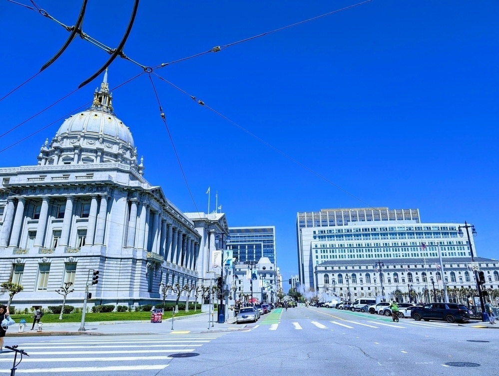 A blue tinted view on a sunny weekday looking north along Dr. Carlton B. Goodlett Place, with San Francisco City Hall on the left, from the intersection with Grove Street in San Francisco's Civic Center neighborhood