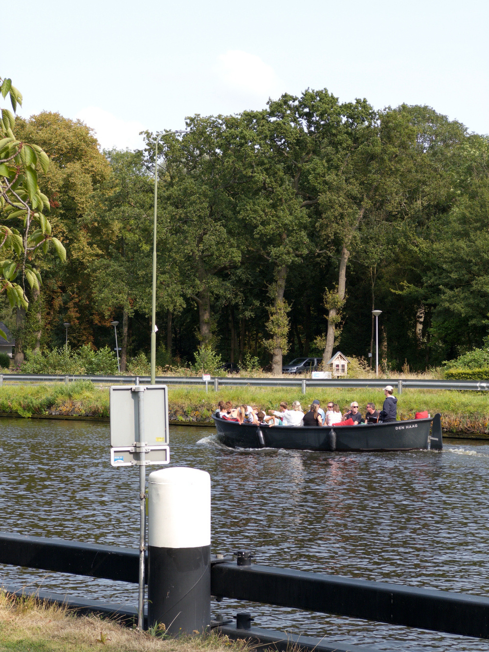 Auto-generated description: A group of people is enjoying a boat ride on a calm river surrounded by lush greenery.