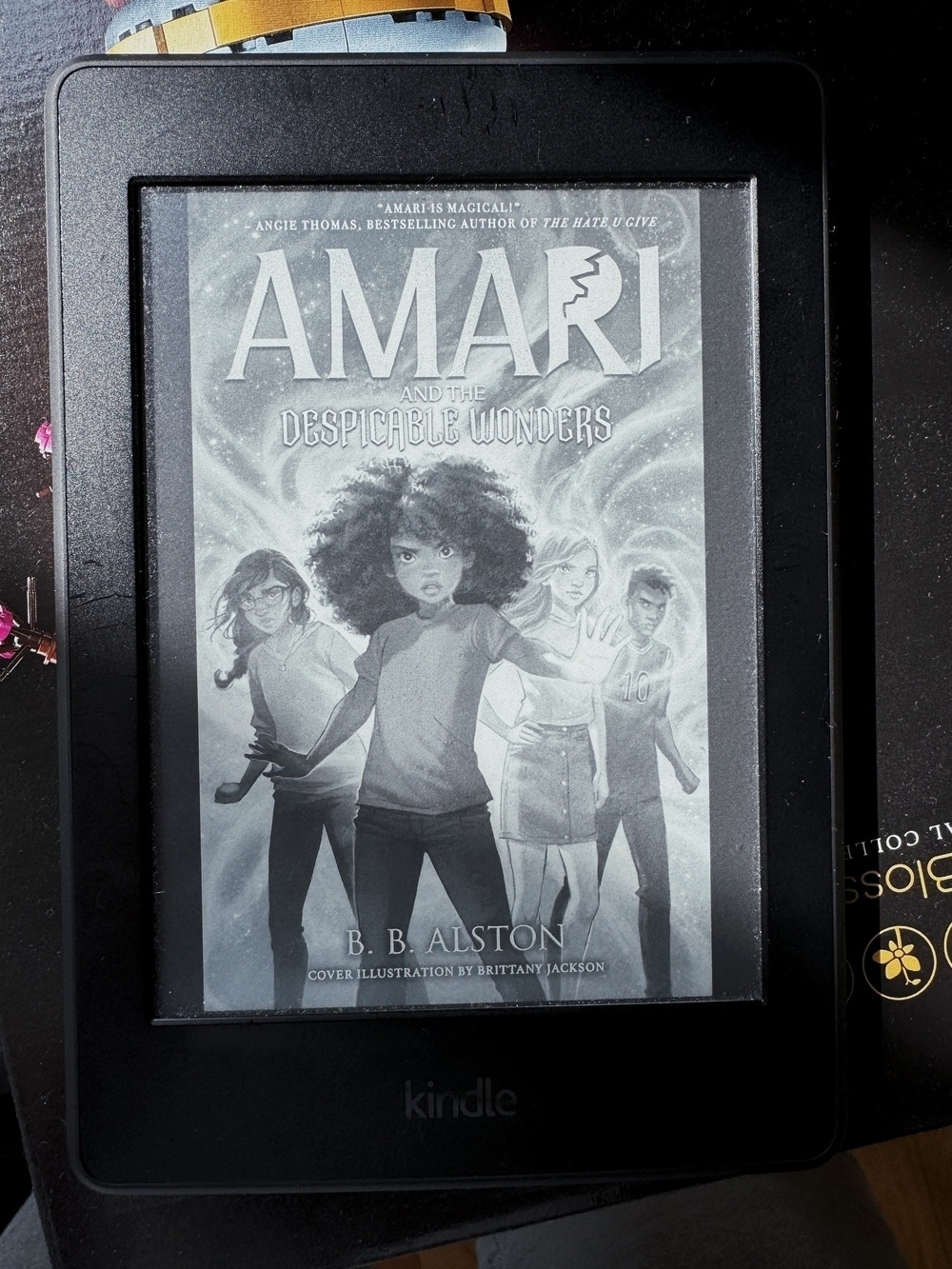 A Kindle device displays the cover of "Amari and the Despicable Wonders" by B.B. Alston, featuring an illustration of diverse characters.