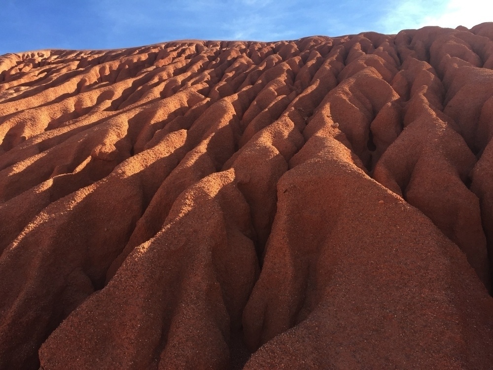 Heavily eroded hillside, deep incising cuts in a very reddish comglamerate.