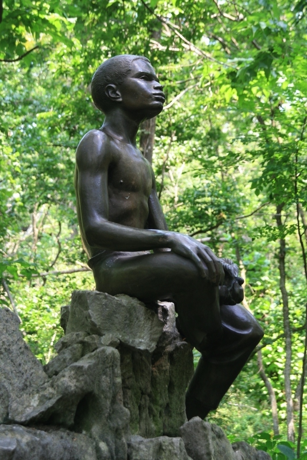 Statue of a young boy sitting on a rock