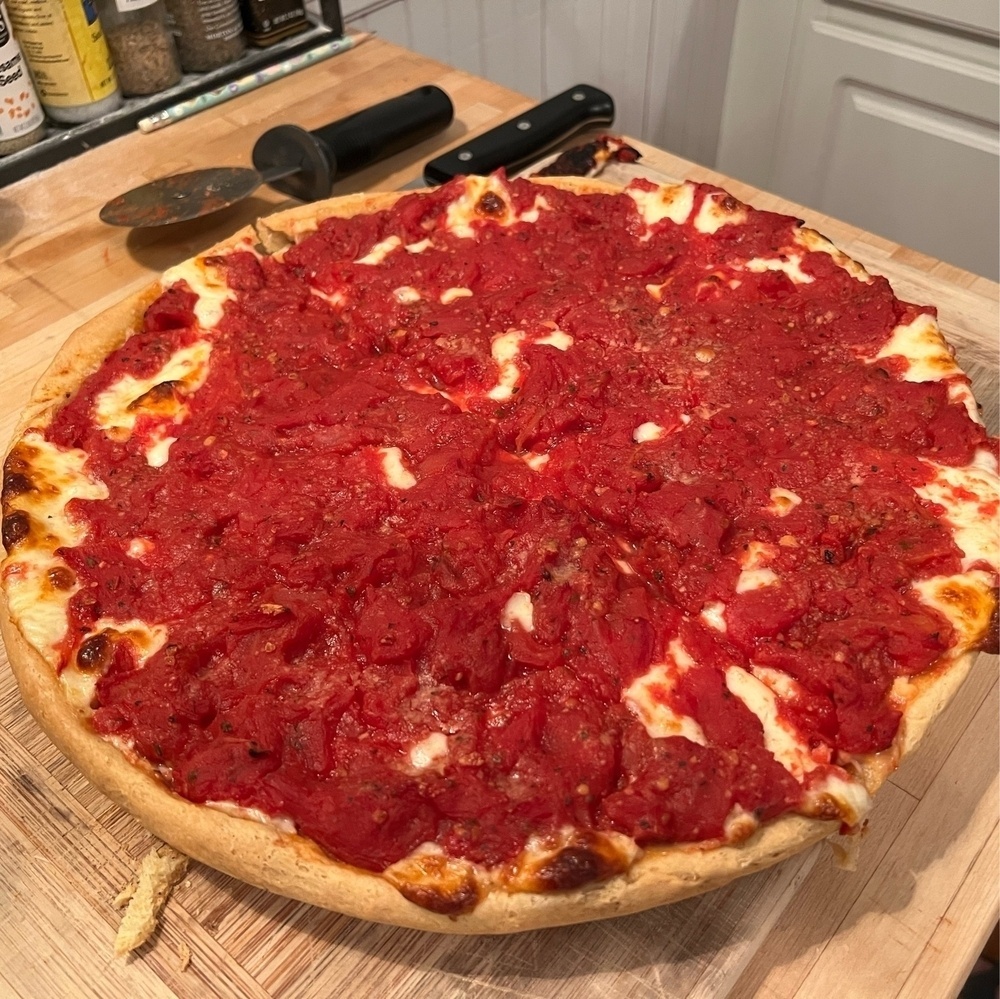 Picture of a large deep dish Chicago pizza with red tomatoes on top.