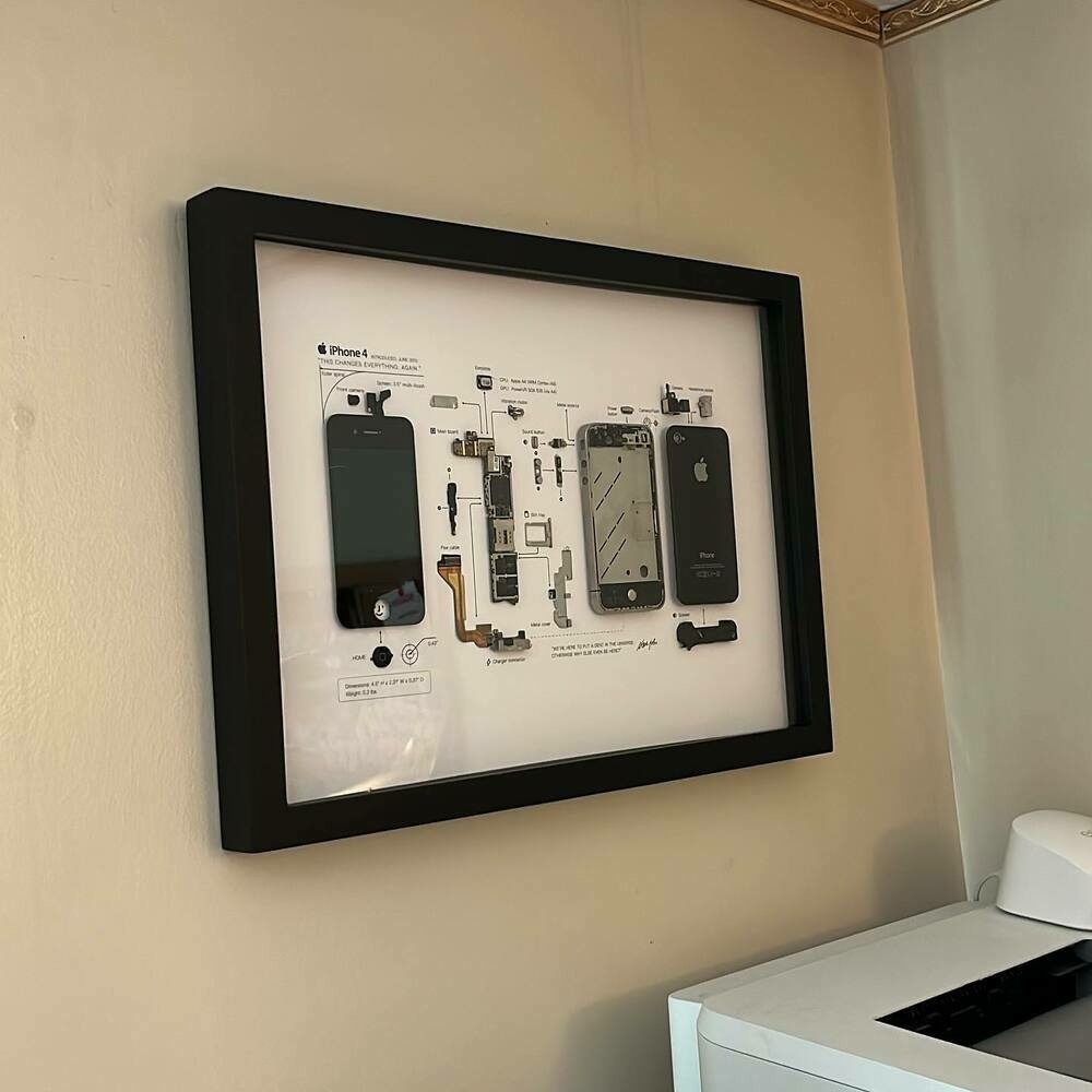 A Grid Studio frame containing a disassembled iPhone 4 hanging on the wall.