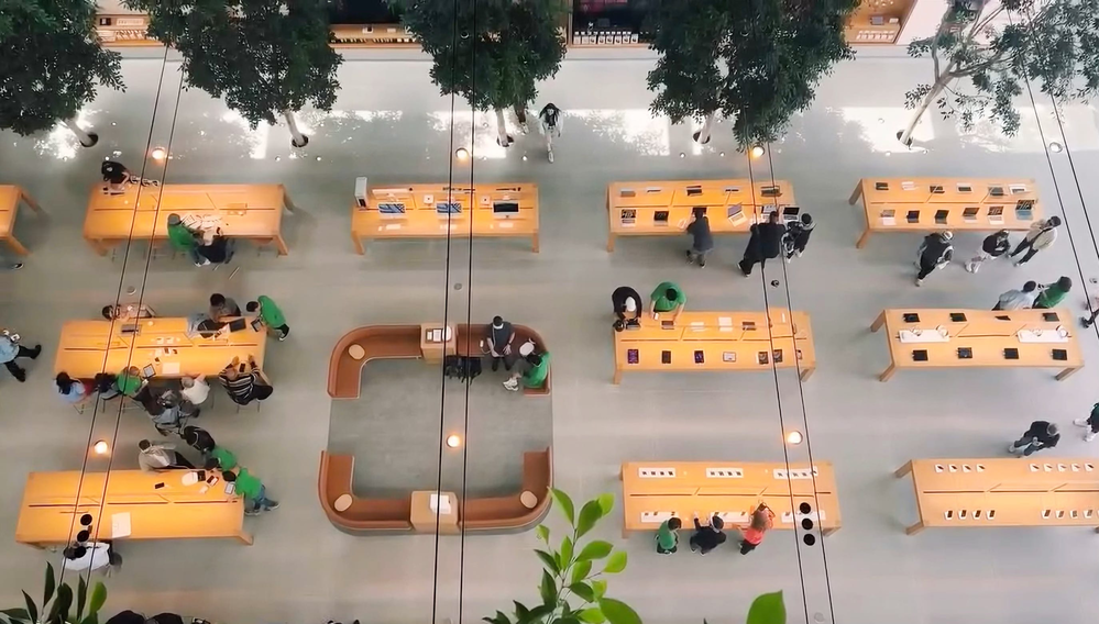 Top down view of an Apple Store with couches arranged in a rounded square shape among other tables.