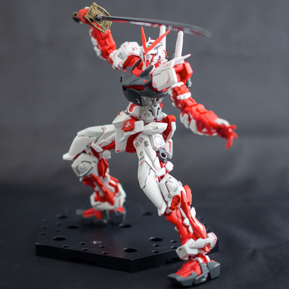 Completed Real Grade Gundam Astray Red Frame model kit posed with the Gerbera Straight katana held over it’s head in a fighting stance.