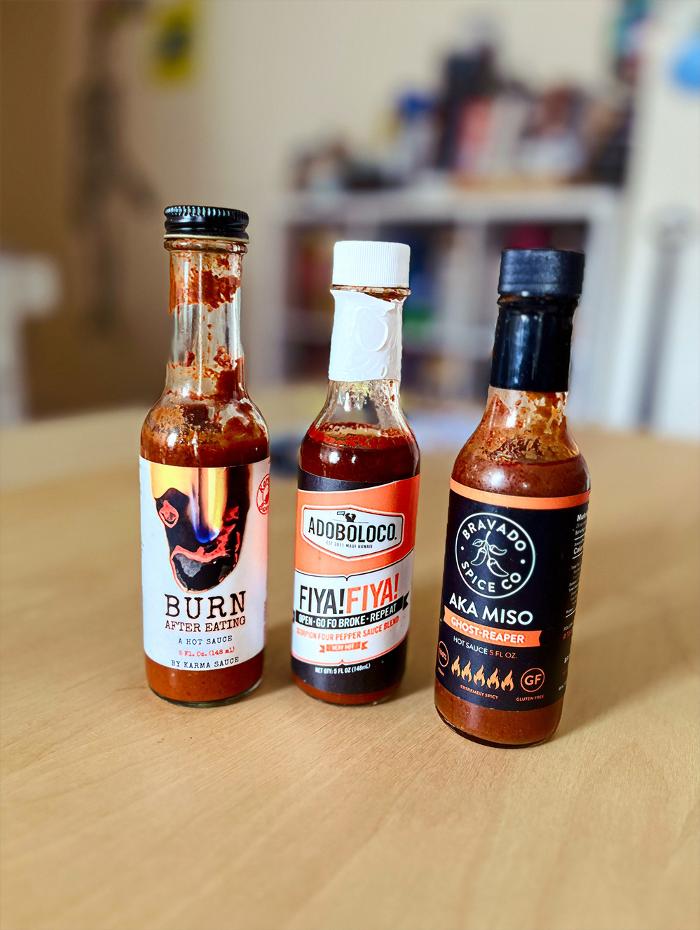 Three bottles of hot sauce of different kinds. From left to right: ￼Burn, Fiya Fiya, and aka miso