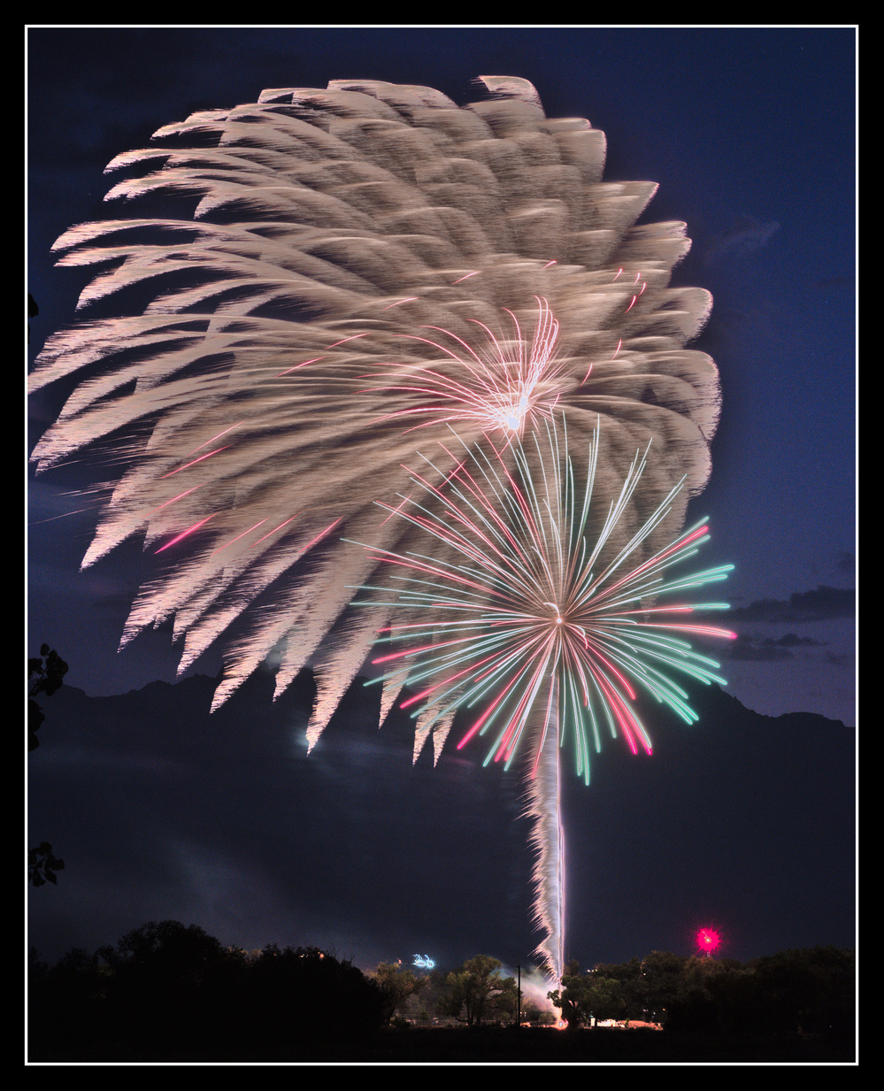 A large firework is blurred to the
     left by wind.