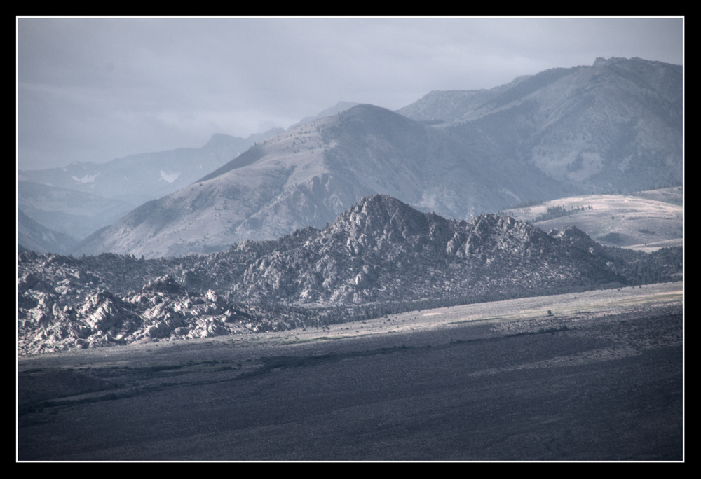 Rough, bouldered hills spring out of a tilted alluvial plain coming from higher mountains off camera.