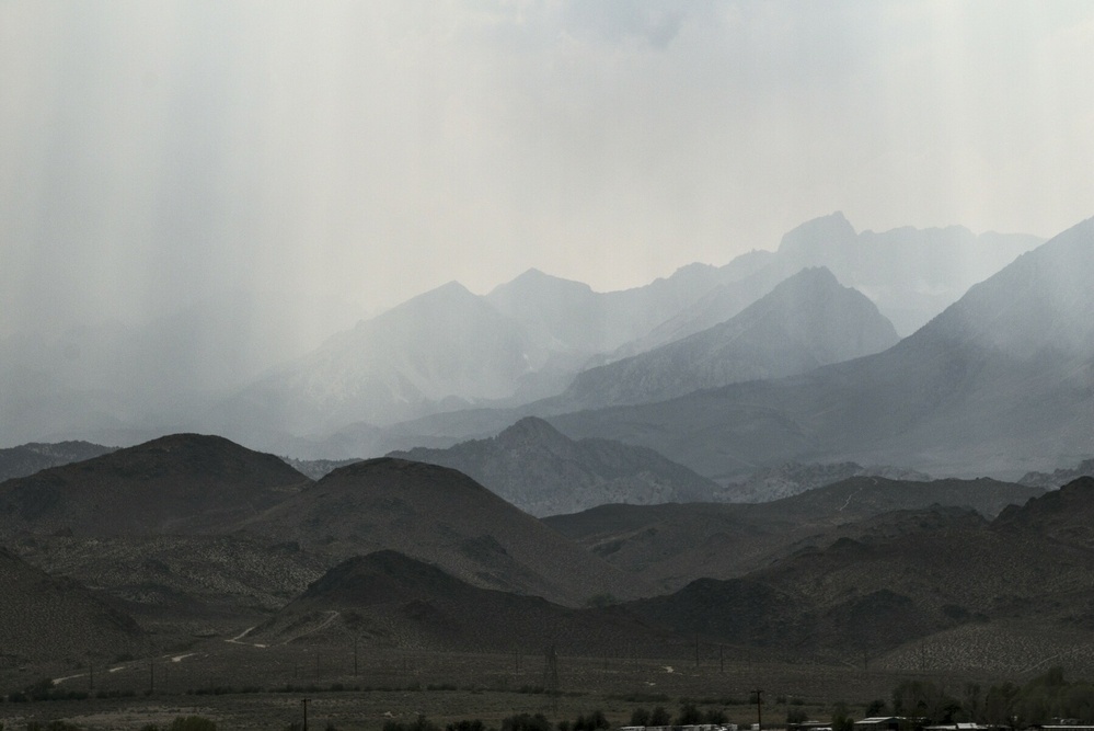 Rising, receding foothills are dimmed by smoke.
