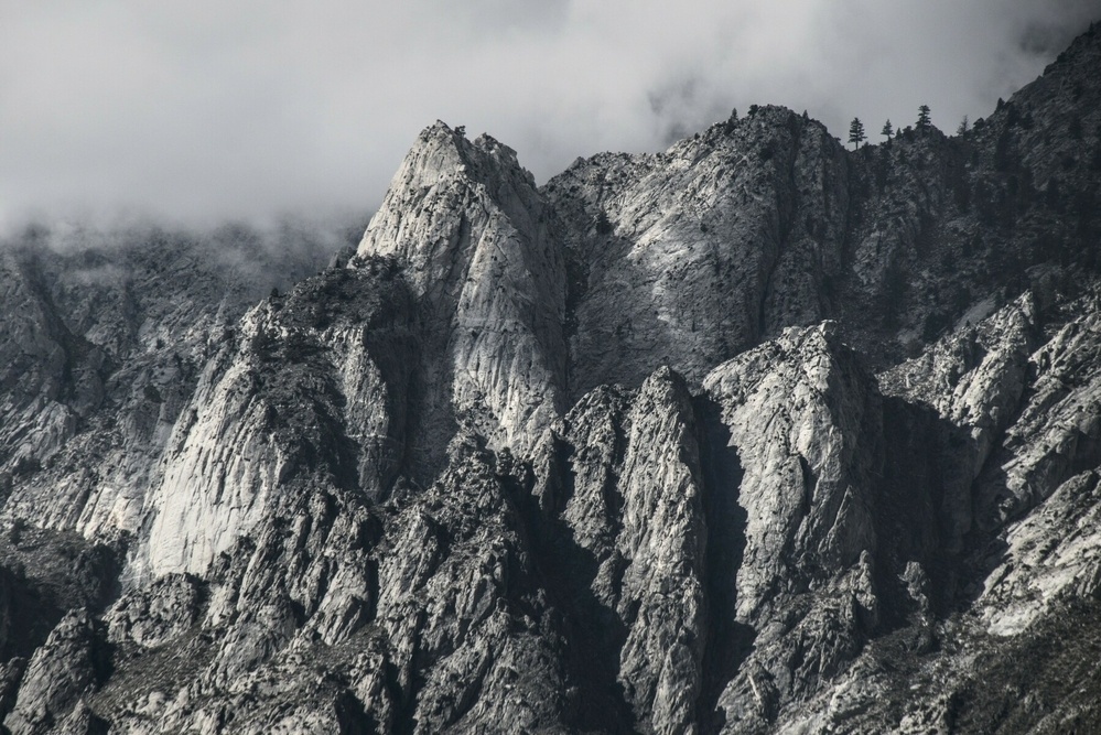 A cluster of granite spires lie below foggy clouds.