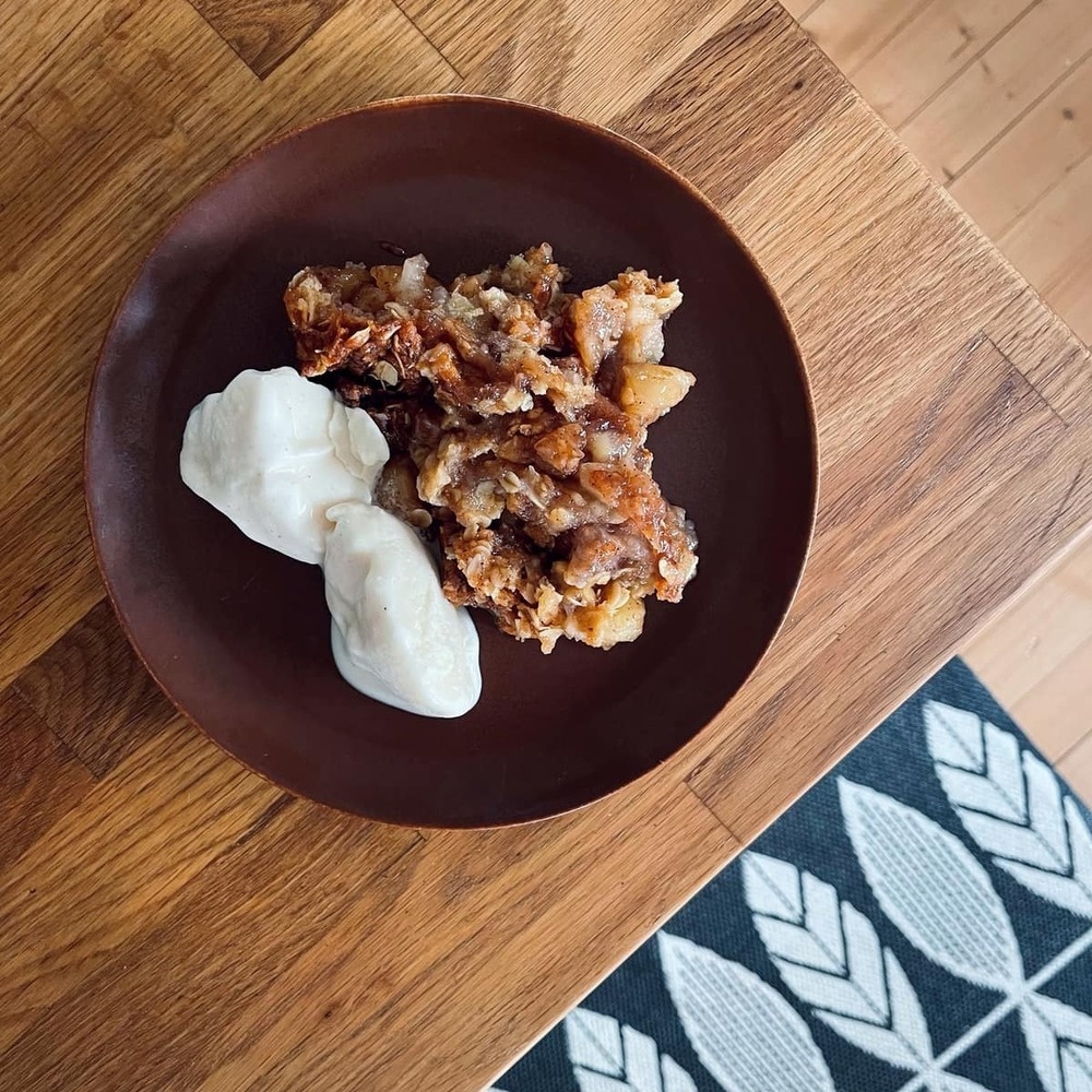 Tasty-looking apple pie and vanilla gelato on a brown, small plate.