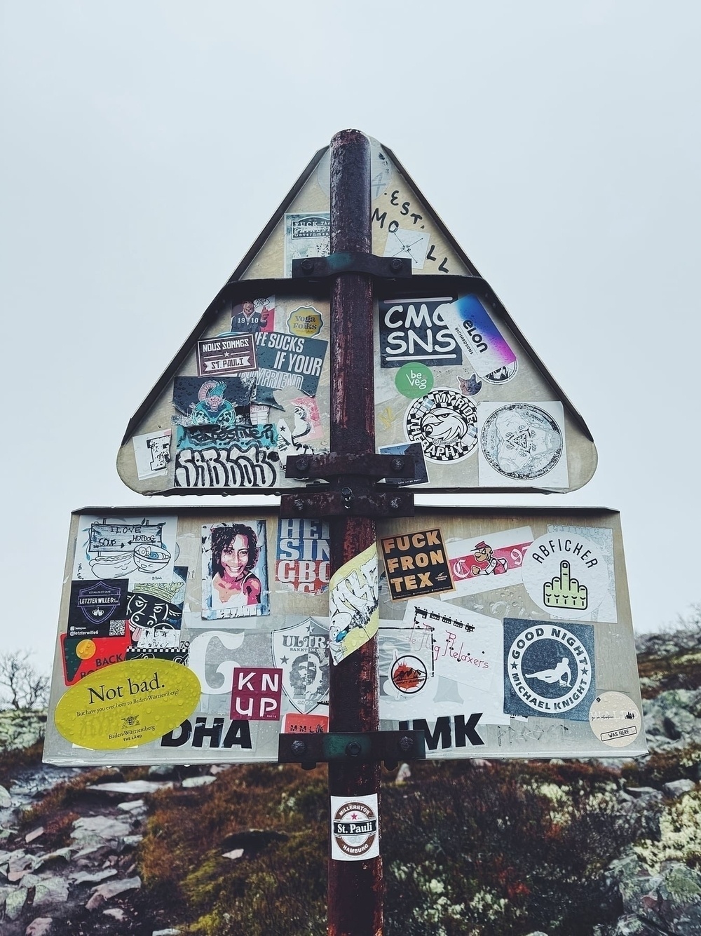 The backside of a warning sign, filled with stickers.