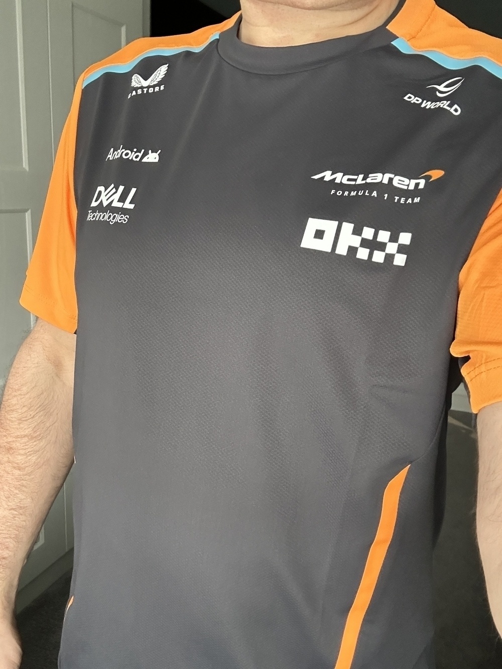 Person wearing a McLaren team t-shirt with various sponsor logos