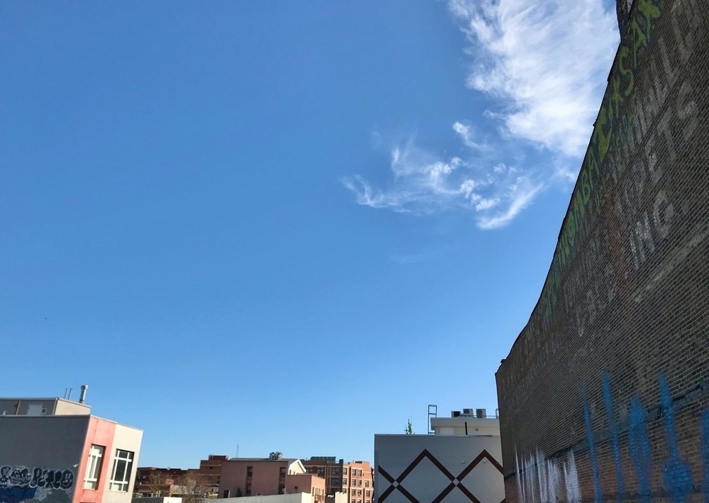 Photo of buildings against the sky, with a swirl of clouds in the corner