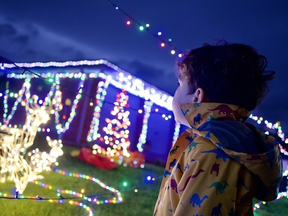 A toddler enjoys colourful Christmas lights.