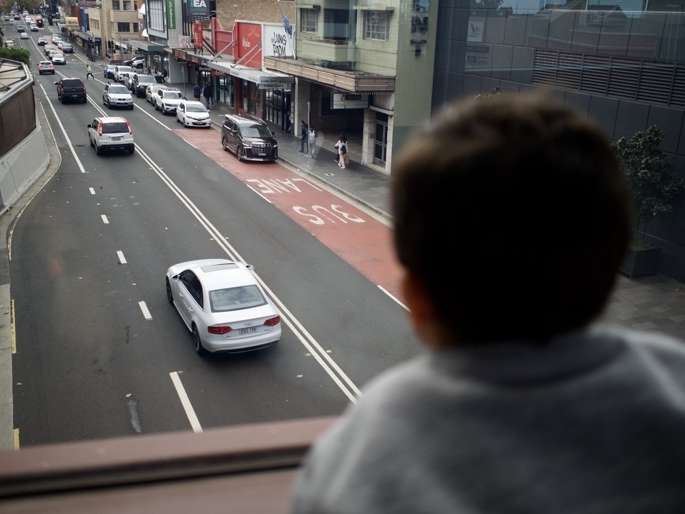 Looking over a child’s shoulder from a walking bridge down at traffic