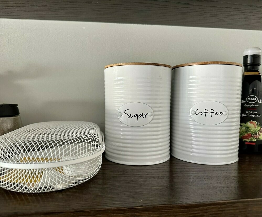 Shelf with white metal sugar and coffee canisters.