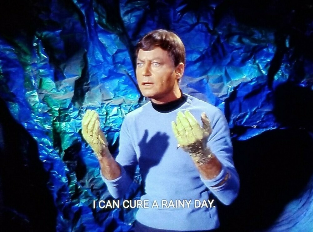 TOS scene. Bones is standing in a cave. (If I had a nickel..) He's in uniform and his sleeves are rolled up. He's holding up  his hands and they are both fully covered in green pasty goop. Closed caption reads, 