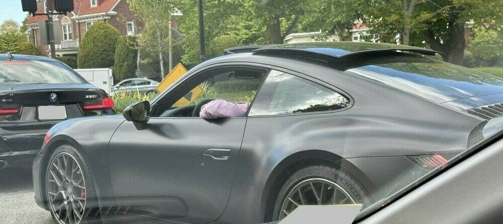 A matte black Porsche 911 stopped in traffic.