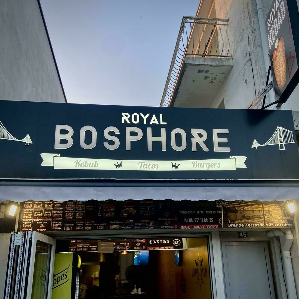 The sign of a kebab place called Royal Bosphore with the words kebab, tacos, and burgers written in the Lobster typeface.