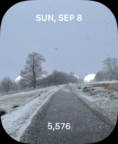 An Apple Watch phase showing a photograph of a snowy scene but the time is hiding well below the horizon 