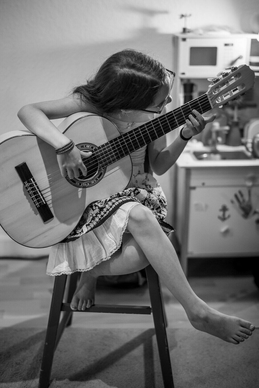 Monochrome image of my daugther sitting on a chair playing her guitar