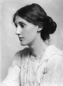 black and white photo of Virginia Woolf in profile wearing a white top and with her hair pulled back into a bun.