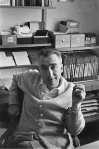 black and white photo from the 1960s with a man smoking a cigarette in his office