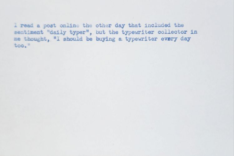 Typed index card in blue ink that reads: I read a post online the other day that included the sentiment "daily typer", but the typewriter collector in me thought, "I should be buying a typewriter every day too."