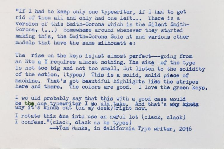 White index card with the following quote typed onto it in blue elite typeface: If I had to keep only one typewriter, if I had to get rid of them all and only had one left... There is a version of this Smith-Corona which is the the Silent Smith-Corona. [...] Somewhere around whenever they started making this, the Smith Corona Silent and various other models that have the same silhouette. The rise on the keys is just almost perfect—going from an N to a Y requires almost nothing. The size of the type is not too big and not too small. But listen to the solidity of the action [types]. This is a solid, solid piece of machine. That's got beautiful highlights like the stripes here and there. The colors are good. I love the green keys.  I would probably say that this with a good case would be the one typewriter I would take. And that's why it's kinda out [on my desk] right now.  I rotate this one into use an awful lot. [He types: clack, clack]  I confess. [clack, clack again as he types.] —Tom Hanks, in California Typewriter, 2016