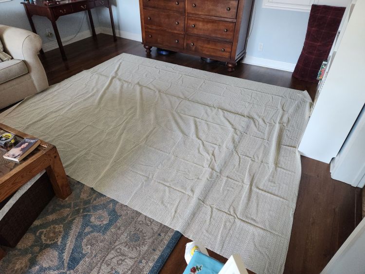 Large 8x10 foot anti-slip rug mat laid out on a living room floor for cutting up.