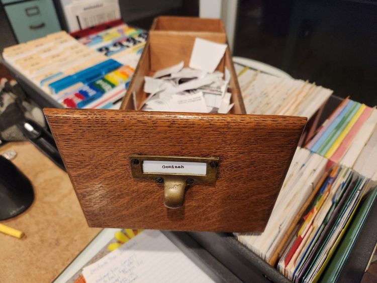 Wooden card index drawer full of trashed index cards with the typed label "Genizah". It sits on top of another drawer full of about 10,000 index cards.