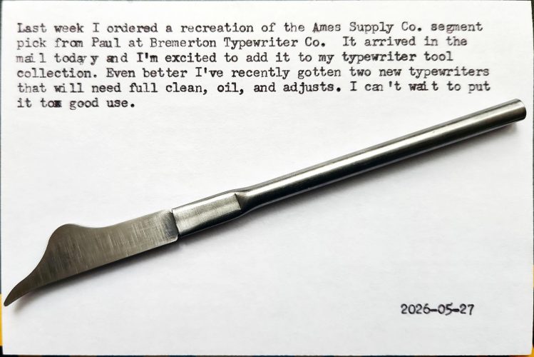 A pen-sized typewriter segment pick with a curved-shaped tip at the end of a thin metal shaft. It sits on top of a typewritten index card that reads: Last week I ordered a recreation of the Ames Supply Co. segment pick from Paul at Bremerton Typewriter Co. It arrived in the mail today and I'm excited to add it to my typewriter tool collection. Even better, I've recently gotten two new typewriters that will need full clean, oil, and adjusts. I can't wait to put it to good use.