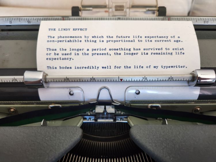 A typed index card in the platen of a typewriter which reads: 
