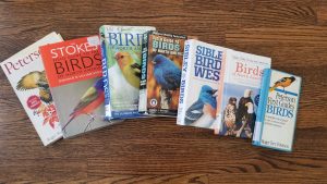 seven large handbooks on birds spread out on the floor