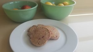 plate with three Welsh cakes on it in front of two bowls of fruit