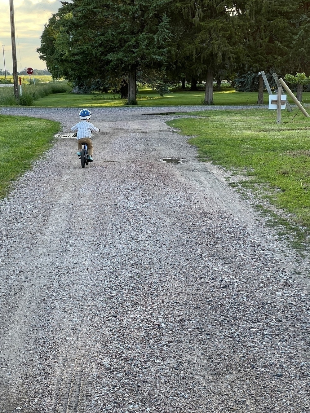 my almost 4 year old son, riding his bike on a gravel road after we installed pedals
