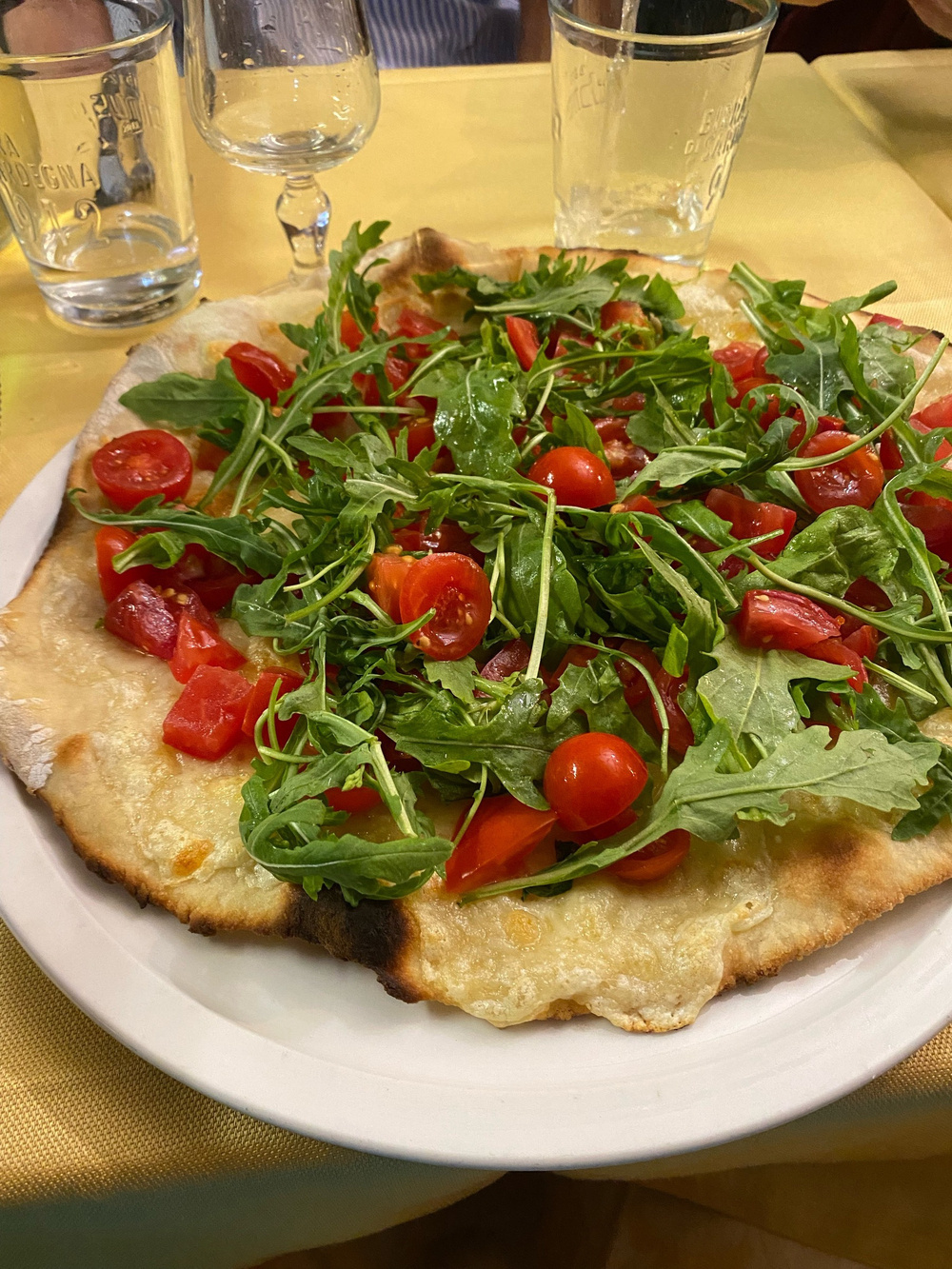 A pizza with vibrant red cherry tomatoes and green rocket leaves. 
