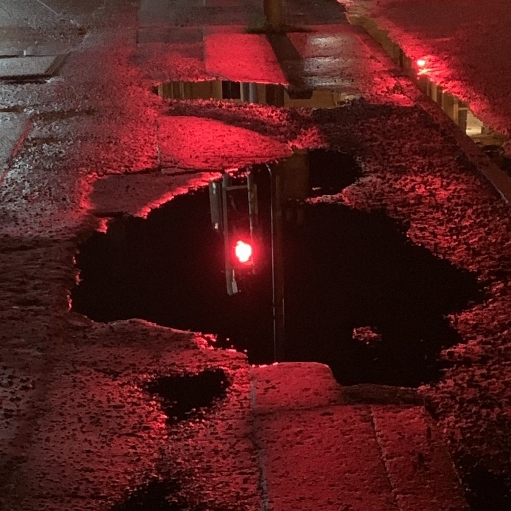 Stoplight at night reflected in puddle