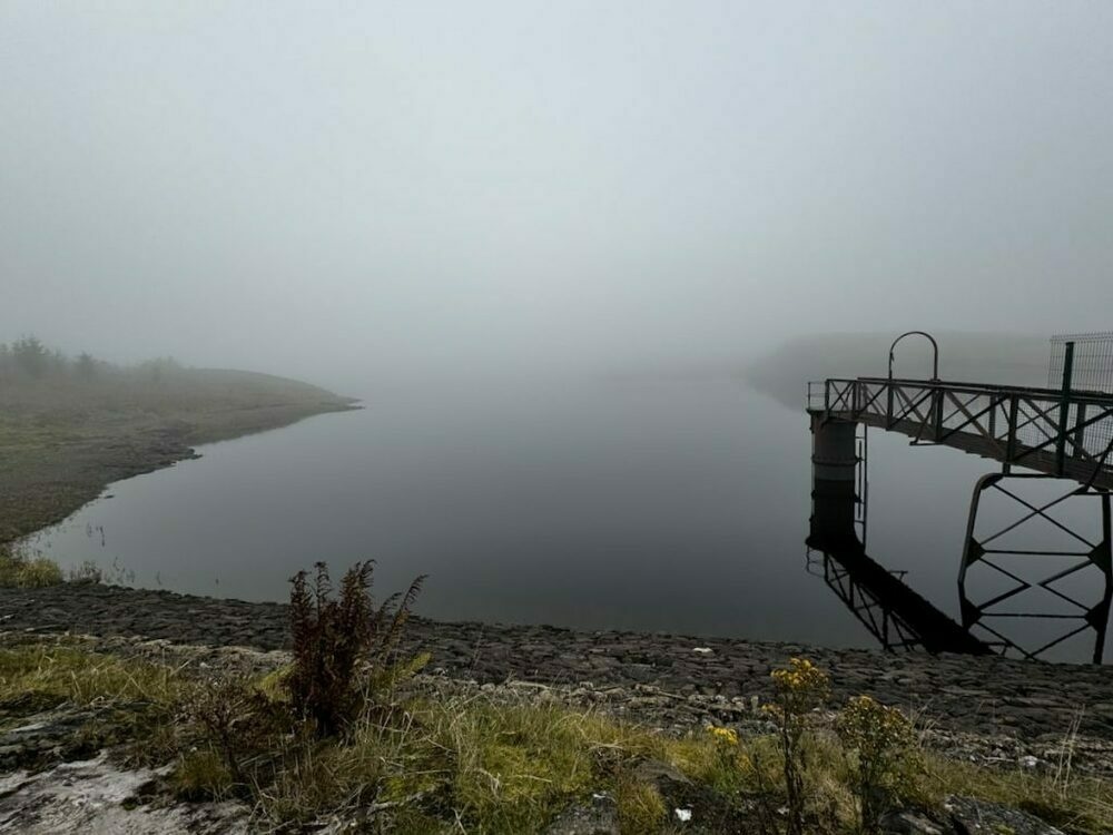 Misty scene at Jaw Reservoir with a pier over calm water and a foggy shoreline.
